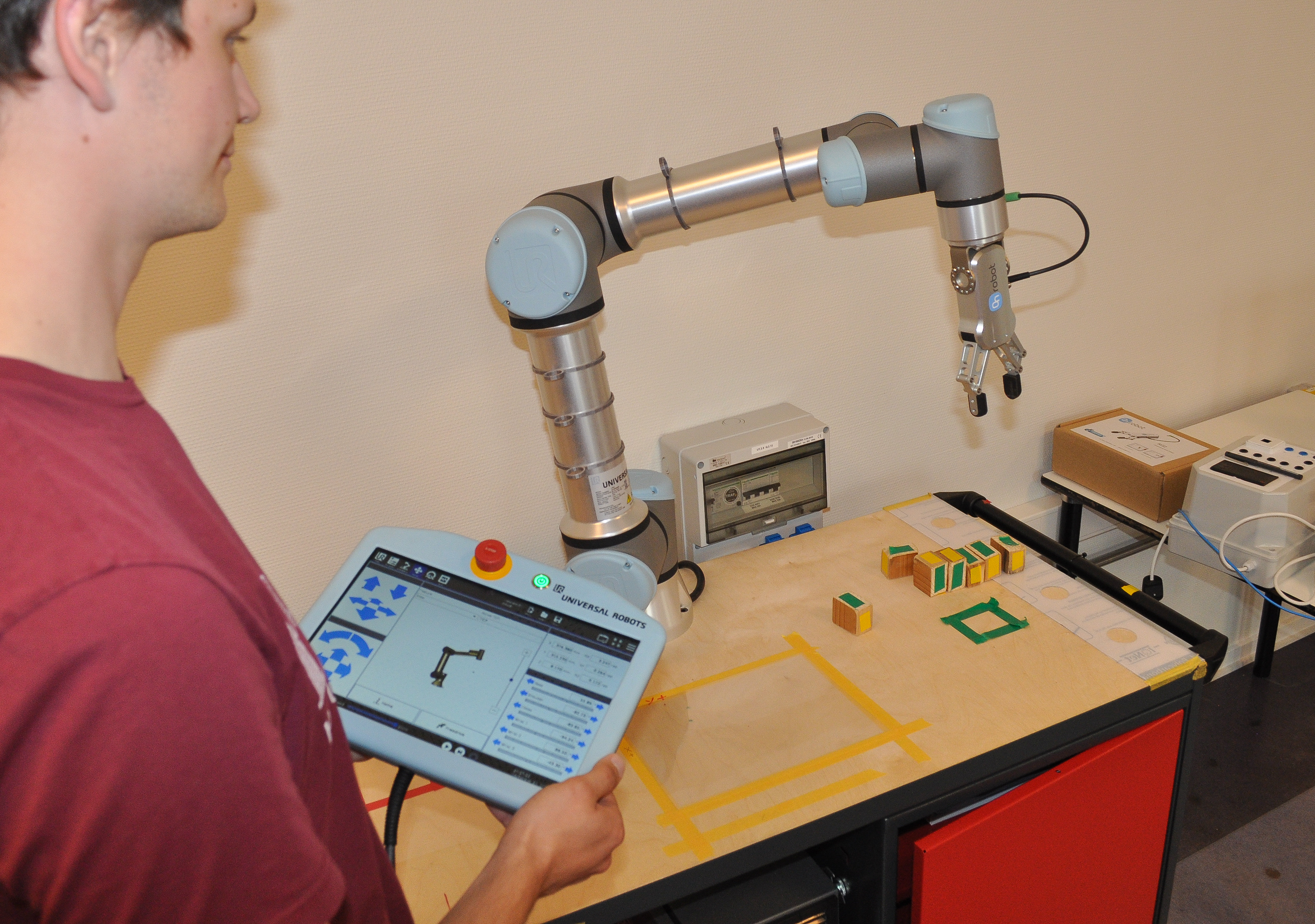 Automationsteknolog fremviser robotarmen med et Teach-betjeningspanel 